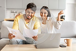 Happy couple analyzing financial documents at home