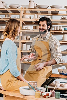 happy couple in aprons with ceramics and paints