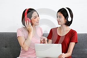 Happy Couple  asia woman wear headphones and enjoy musics playing mobile phone and tablet in bedroom
