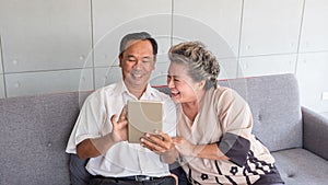 Happy couple asian senior retired using mobile tablet application technology for social network among friends community via