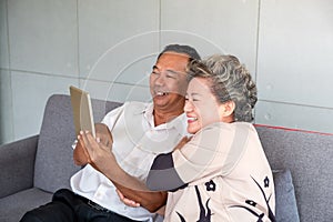 Happy couple asian senior retired using mobile tablet application technology for social network among friends community via