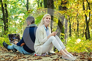Happy couple on autumn walk. Business couple - man browsing Internet on a notebook, woman using mobile phone outdoors
