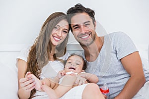 Happy couple with baby relaxing on bed