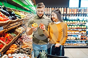 Happy couple with basket in grocery store