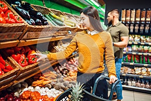 Happy couple with basket in grocery store