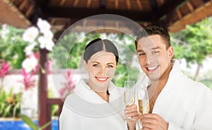 Happy couple in bathrobes with champagne at resort