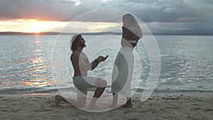 Happy couple, beach and proposal in sunset for engagement, marriage or commitment together. Man on knee for woman