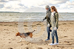 Happy couple with beagle dog on autumn beach