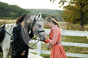 Happy couple and beautiful white horse. Loving couple with horse on ranch.