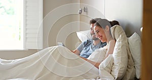 Happy couple, bed and laughing with tablet, touch and kiss while on vacation or relaxing at home. Man, woman and bonding