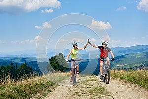 Happy couple bicyclists in professional sportswear and helmets riding cross country bicycles