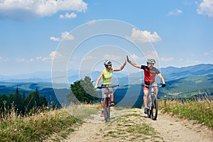 Happy couple bicyclists in professional sportswear and helmets riding cross country bicycles photo