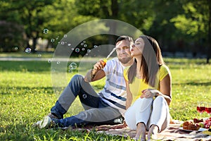 Happy couple blowing soap bubbles in park on spring day