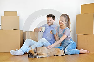 Happy couple with boxes and dog moving to new home
