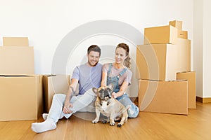 Happy couple with boxes and dog moving to new home