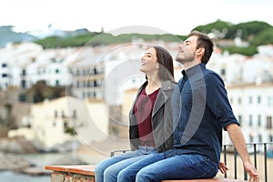 Happy couple breathing on a ledge on vacation