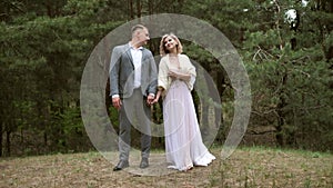 A happy couple, the bride and groom look at each other with a loving gaze on their wedding day outdoors in the forest