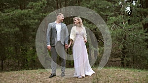 A happy couple, the bride and groom look at each other with a loving gaze on their wedding day outdoors in the forest