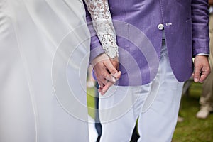 Happy couple, bride and groom at wedding aisle holding hands closeup