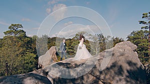 A happy couple of brides stand on the mountain with their backs to the camera and look into the distance at the