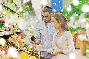 Happy couple buying avocado at grocery store