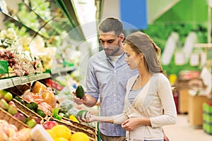 Happy couple buying avocado at grocery store