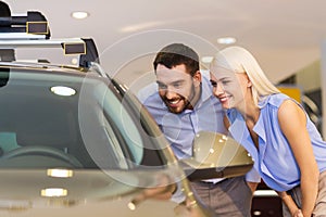 Happy couple buying car in auto show or salon