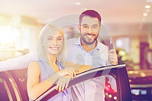 Happy couple buying car in auto show or salon