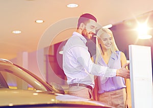 Happy couple buying car in auto show or salon