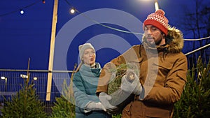 Happy couple buying christmas tree at market