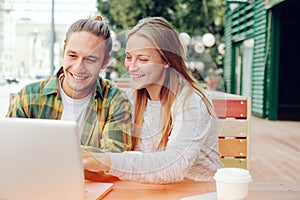 Happy couple in cafe looking at laptop and discussing plans