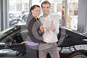 Happy couple with car key in dealership