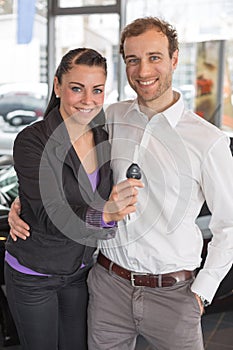 Happy couple with car key in dealership