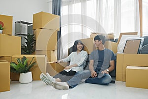 Happy couple with cardboard boxes in new house at moving day.