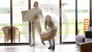 Happy couple carrying boxes entering new house, home owners moving