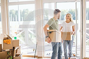 Happy Couple Carrying Cardboard Boxes Into New Home On Moving Day