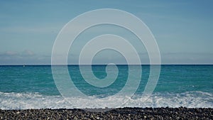 Happy couple in casual clothes walking along the sea holding hands on warm sunny day. Turquoise sea, waves, good mood