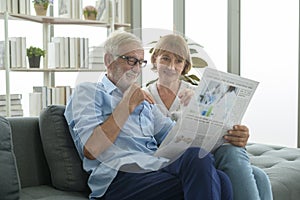 Happy Couple Caucasian senior are relaxing , reading newspaper in living room