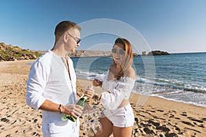 Happy couple with champagne on the beach. Summer vacations concept. Top view