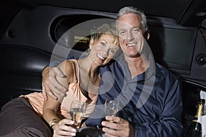 Happy Couple With Champagne Sitting In Limousine