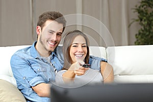 Happy couple changing channel on tv