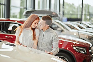 Happy couple chooses first family car to buy in a showroom