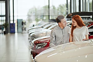 Happy couple chooses first family car to buy in a showroom