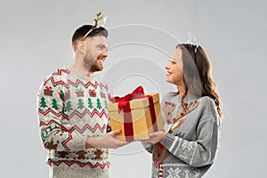 Happy couple in christmas sweaters with gift box