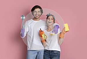Happy Couple With Cleaning Tools In Hands Posing On Pink Background