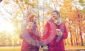 Happy couple with coffee walking in autumn park