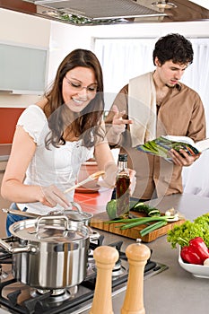 Happy couple cook in kitchen with cookbook