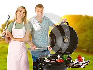 Happy couple cooking on barbecue grill. Picnic time