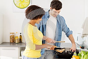 Happy couple cooking food at home kitchen