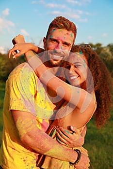 Happy couple covered with colorful powder dyes outdoors. Holi festival celebration